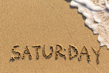 Week series - SATURDAY - written on a sandy beach with the soft wave at sunny day.