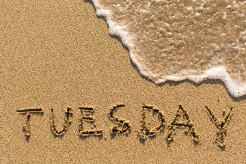 Fototapeta premium Week series - TUESDAY - written on a sandy beach with the soft wave at sunny day.