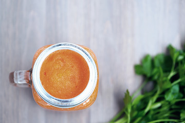 Healthy carrot smoothie in a jar on wooden background with parsley. Cold toning. Shallow dof