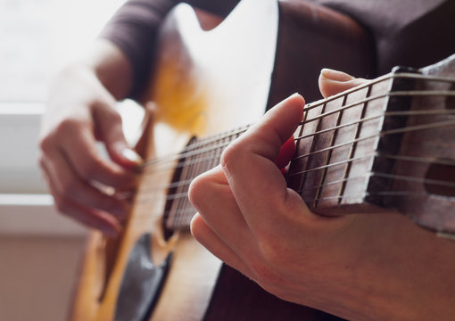 woman's hands playing acoustic guitar