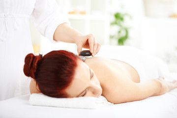 Obraz na płótnie Canvas Woman having hot stones on her back in spa salon
