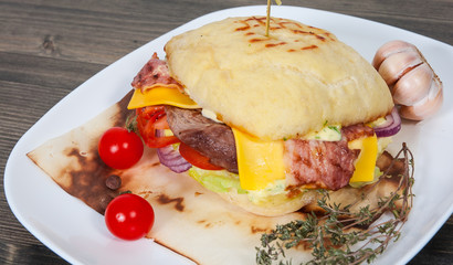 burger with meat, tomato, onion, cheese, lettuce on wooden table