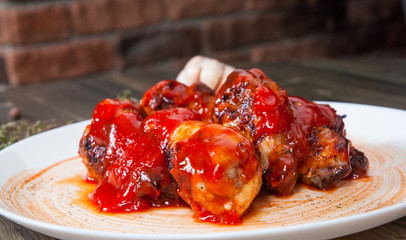 Chicken wings in red tomato sauce on wooden table