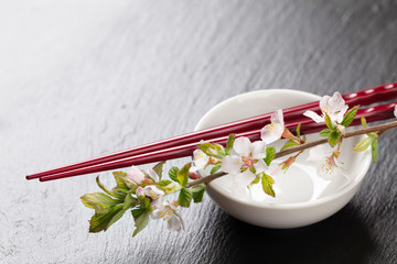 Japanese sushi chopsticks, soy sauce bowl and sakura blossom