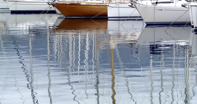 riflesso di prue di barche a vela ormeggiate su superficie increspata