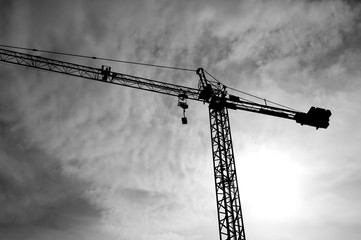 Construction crane bottom view in operation with cloud sky background. Black&White photo.