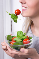 young woman eating salad with tomatoes and spinach