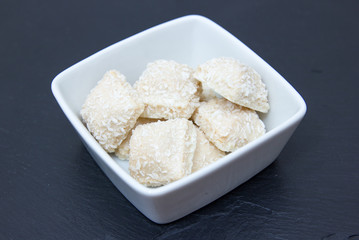 Cakes with coconut on a square bowl on slate top