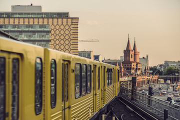 Naklejka premium Yellow Subway train on trail to the historical bridge (Oberbaumbruecke) in Berlin, Germany, Europe, Vintage filtered style 