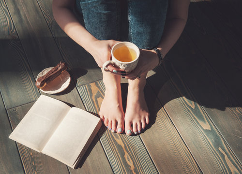 Cozy photo of young woman with cup of tea sitting on the floor