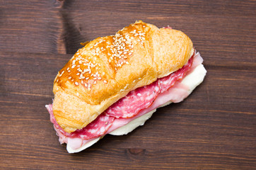 Cornetto savory filling with salami on wooden table seen from above
