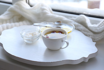Tea set on a white wooden tray on the windowsill