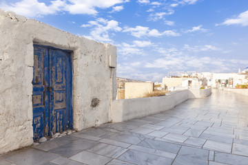 Paved avenue and old blue door in Oia