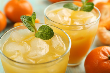 Fresh cocktails with ice, mint and tangerines on the wooden table, close up