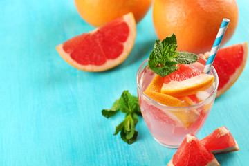 Ripe grapefruits and fresh juice with mint on blue background, close up