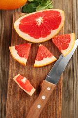 Sliced grapefruits with mint on wooden board, close up