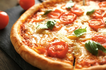 Margherita pizza with tomatoes on slate plate, close up