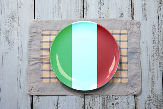 Empty plate with Italian flag on light blue wooden background