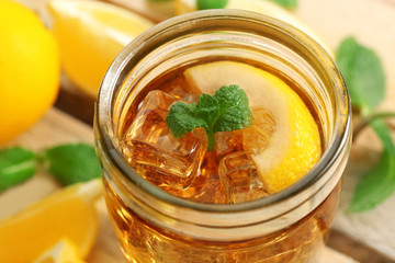 Jar of iced tea with lemon on wooden background
