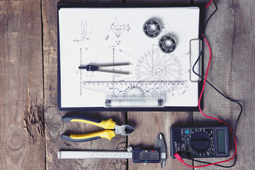 Digital multimeter and laptop on a wooden background.