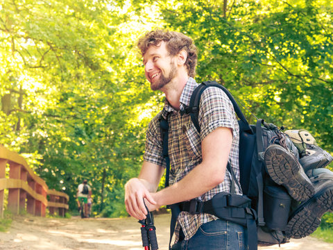 young man with backpack hiking in forest trail