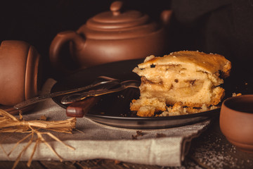 Piece of pie and pottery for tea on an old wooden table