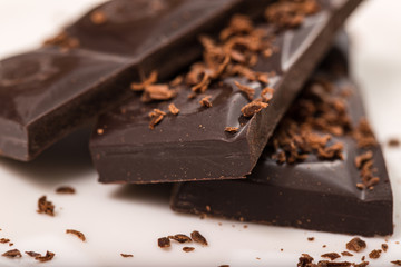 Pieces from a chocolate bar and chocolate crumbs on a white back