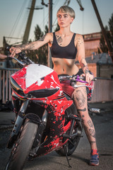 Fototapeta na wymiar Girl with tattoos sitting on a motorcycle