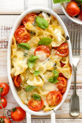 Casserole with farfalle pasta, cherry tomato, mozzarella cheese and herbs