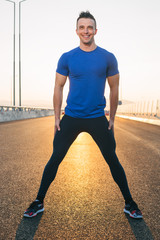 Portrait Of Male Runner On highway sunset, streching legs