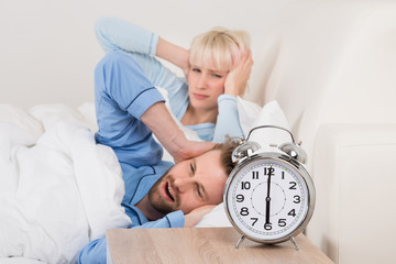 Young Couple Awakened By Alarm Clock