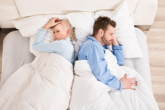 Sad Couple Lying On Bed