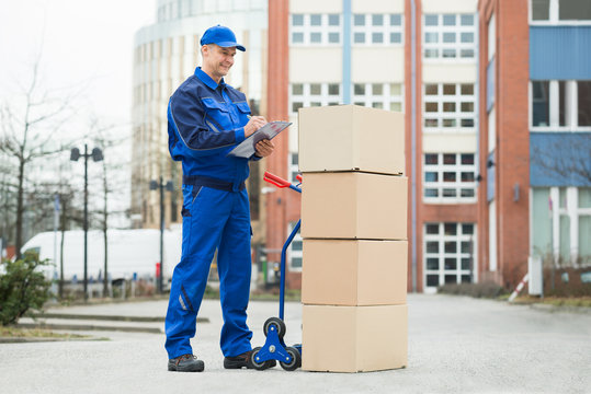 Portrait Of Delivery Man With Parcels And Clipboard