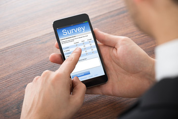 Businessman Filling Online Survey On Mobile Phone