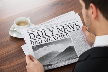 Businessman Reading Weather News On Newspaper