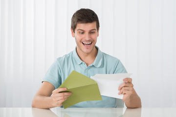 Happy Man Holding Letter On Desk