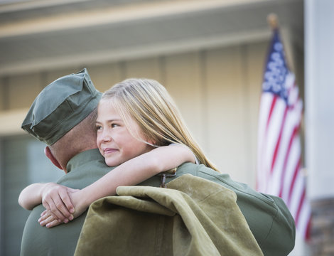 Returning Caucasian soldier hugging daughter