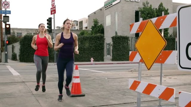 Rebel adventurous intense female athlete runner jogger team urban fitness through construction closed road
