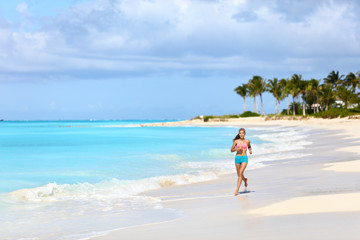 Fototapeta na wymiar Fitness runner woman running on tropical white sand beach nature landscape outdoors. Beautiful nature in Caribbeans with person jogging living a healthy lifestyle for weight loss in summer.
