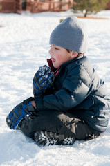 Fototapeta na wymiar Adorable little boy in navy coat sitting in snow.