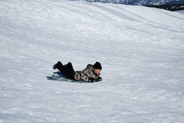 Little kid sledding down snowhill.