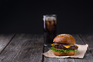 Juicy burger with cold cola on wooden background