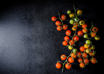 Fresh cherry tomatoes on black wooden background