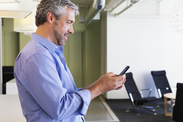 Caucasian businessman using cell phone in office