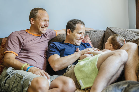 Gay couple playing with baby boy on sofa