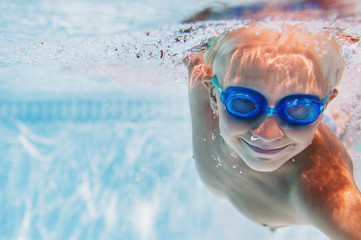 Caucasian boy swimming underwater in pool