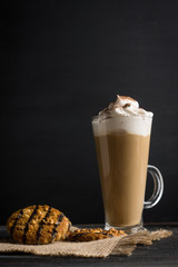Glass of coffee with cookies on wooden background