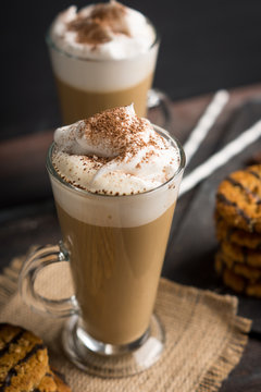 Glass of coffee with cookies on wooden background. Shallow depth of field.