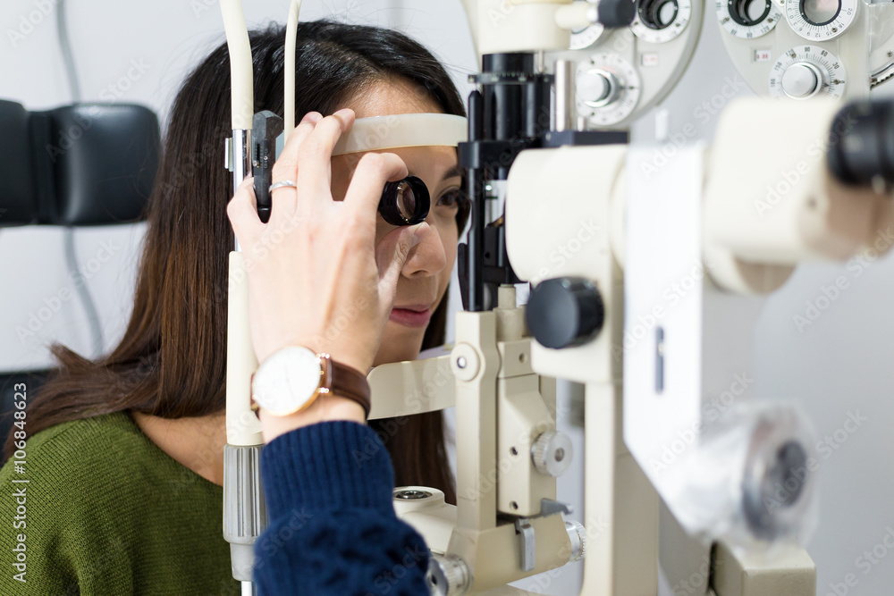 Wall mural woman having her eyes examined by eye doctor