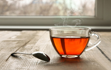 a Cup of fragrant green tea and an iron spoon on wooden background